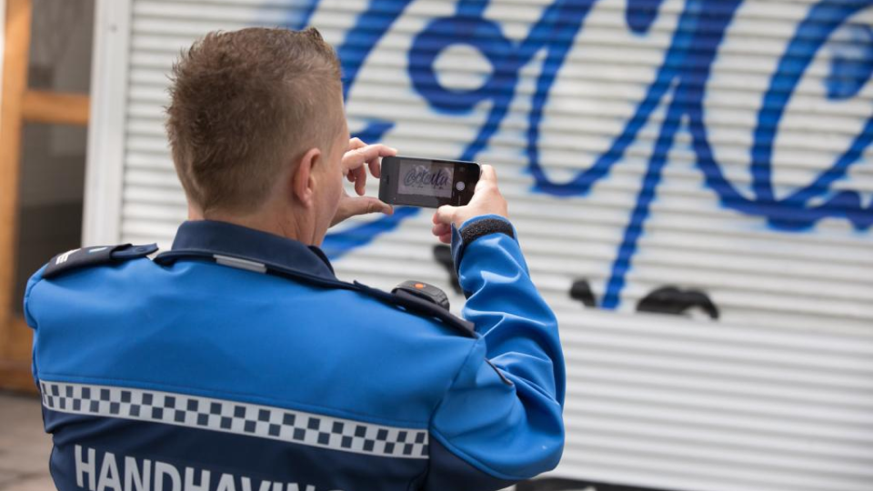 Handhaver fotografeert graffiti met de Spitter app